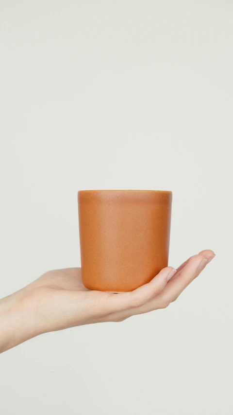 a person holding a cup in their hand, smooth matte, amber, detailed product shot, thumbnail