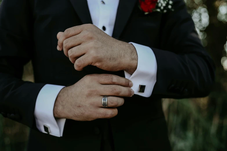 a close up of a person wearing a suit and tie, rings, men in tuxedos, wearing jewellery, hands down