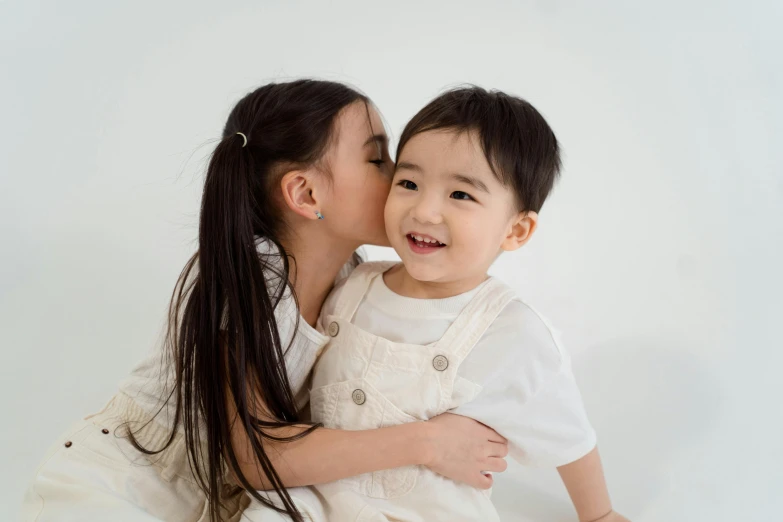 a mother kissing her son on the cheek, by Kim Tschang Yeul, pexels contest winner, mingei, two pigtails hairstyle, young asian girl, with a white background, a handsome