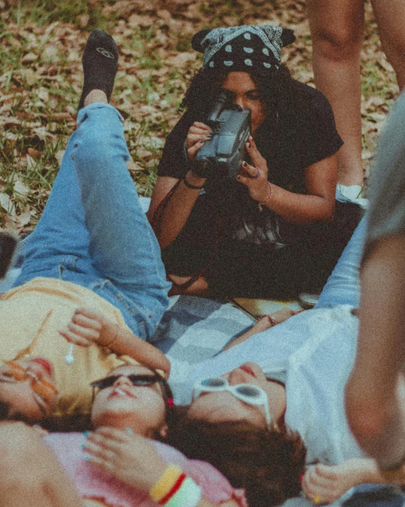 a group of people laying on the ground next to each other, a polaroid photo, trending on pexels, forest picnic, lesbians, with anamorphic lenses, ((oversaturated))