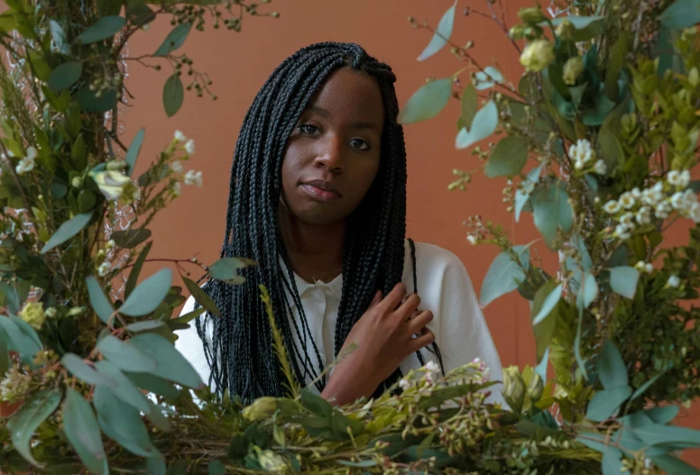 a woman standing in front of a wreath of flowers, by Lily Delissa Joseph, pexels contest winner, hyperrealism, kara walker james jean, covered in plants, lianas, mid length portrait photograph