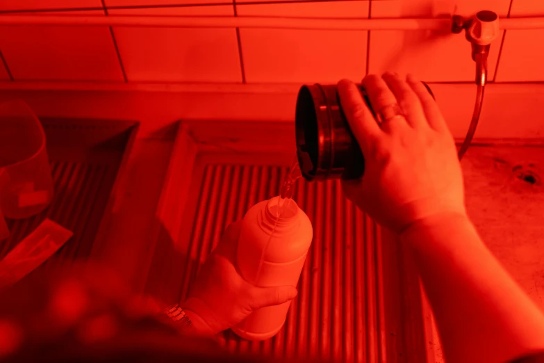 a person is washing their hands in a sink, a picture, by Julia Pishtar, bauhaus, detailed glowing red implants, dim flashlight lighting, thumbnail, glowing jar