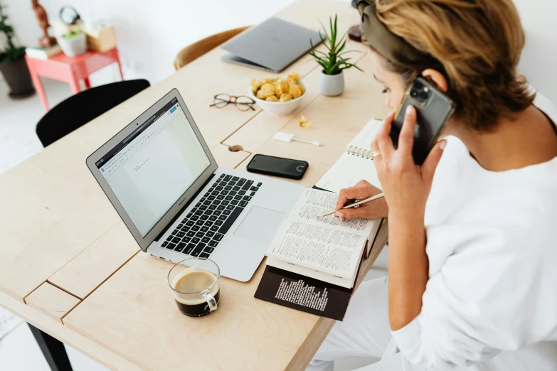 a woman sitting at a table talking on a cell phone, trending on pexels, arbeitsrat für kunst, working on a laptop at a desk, sitting on a mocha-colored table, white backround, middle of the page