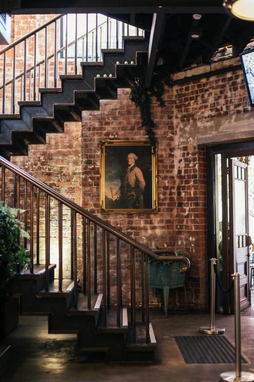 a staircase in a building with a painting on the wall, a portrait, inspired by Sydney Prior Hall, pexels, old brick walls, lush surroundings, in savannah, ignant