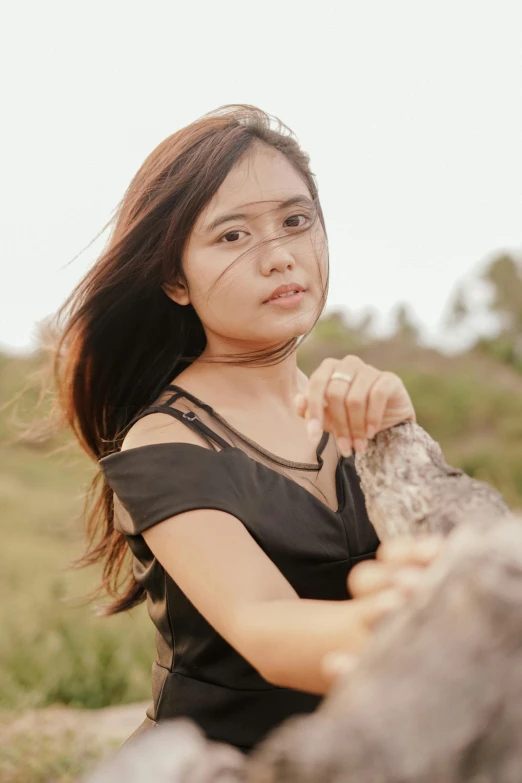 a woman sitting on a rock in a field, pexels contest winner, realism, south east asian with round face, headshot profile picture, 18 years old, scratches on photo