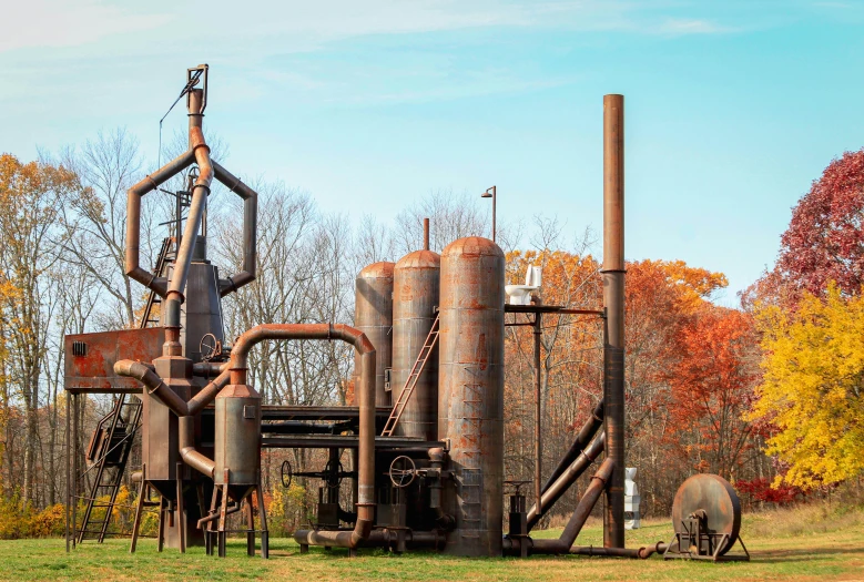 an old factory in a field with trees in the background, inspired by Grant Wood, pexels contest winner, environmental art, iron smelting pits, outdoor art installation, man engine, 8 k hi - res