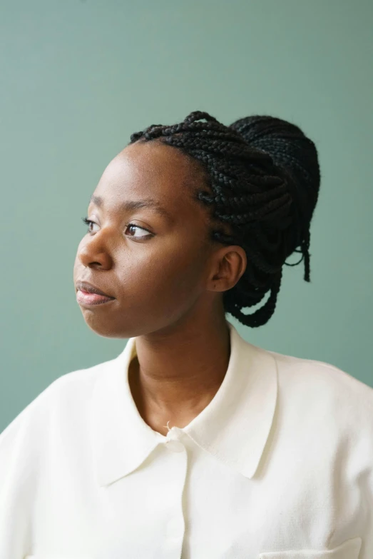 a woman standing in front of a green wall, by Lily Delissa Joseph, hurufiyya, long braided hair pulled back, looking into the distance, on a pale background, student