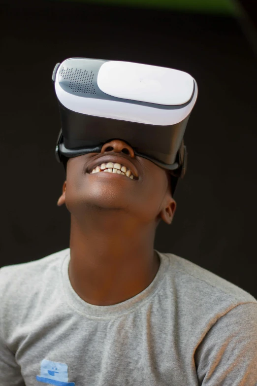 a young man wearing a virtual reality headset, pexels, afrofuturism, brown skin man with a giant grin, smol, head straight down, tech demo