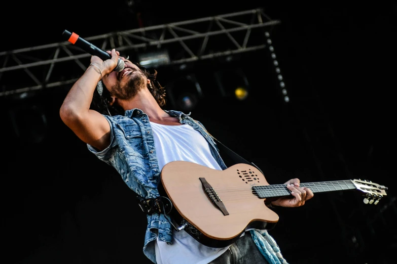 a man holding a guitar and singing into a microphone, by Tom Bonson, pexels contest winner, figuration libre, jason momoa, rapping on stage at festival, robert sheehan, square