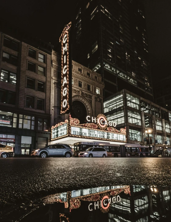 the chicago theater marquee is reflected in a puddle of water, a photo, unsplash contest winner, car shot, background image, beautifully lit buildings, gif