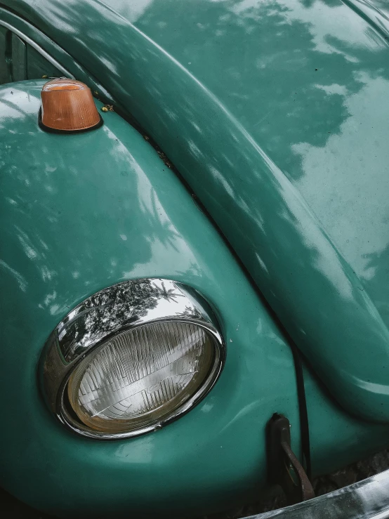 a close up of the front end of a green car, by Adam Marczyński, pexels contest winner, photorealism, retro lights, teal paper, beetle, instagram story