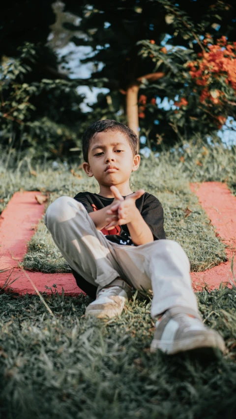 a little boy that is sitting in the grass, an album cover, by Basuki Abdullah, pexels contest winner, confident stance, 15081959 21121991 01012000 4k, black teenage boy, thumbnail