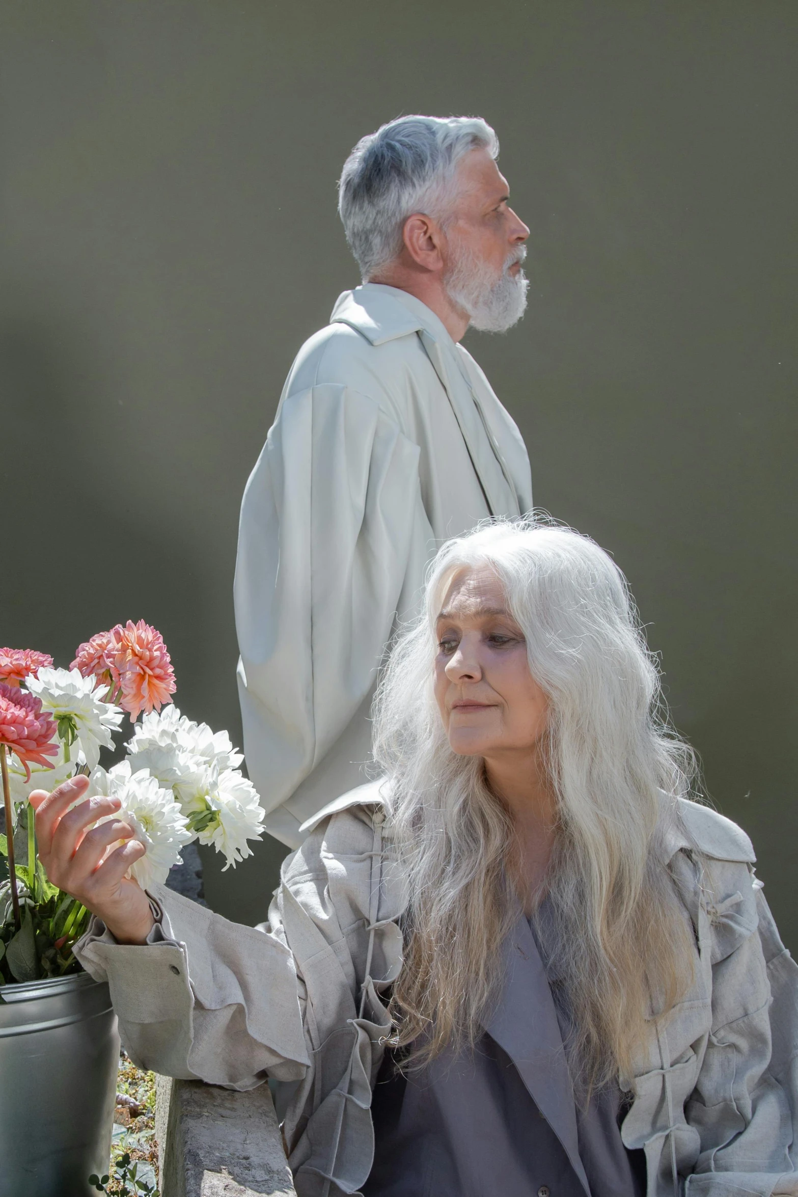 a man and a woman standing next to each other, an album cover, inspired by Grethe Jürgens, renaissance, flowy white grey hair, wearing a hoodie and flowers, ( ( theatrical ) ), funeral