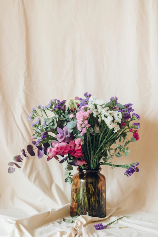 a vase filled with purple and white flowers, pexels contest winner, soft vintage glow, plain background, multicolored, glass jar