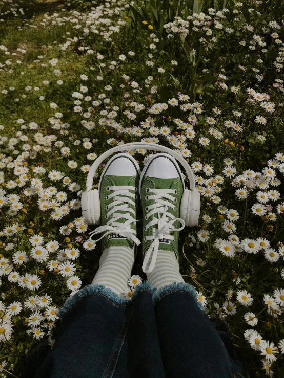 a person sitting in the middle of a field of daisies, an album cover, trending on pexels, acid-green sneakers, with headphones, ((greenish blue tones)), green floor