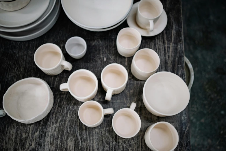 a number of cups and plates on a table, a still life, inspired by Lewis Henry Meakin, unsplash, process art, organic ceramic white, ivory, wide high angle view, chiseled features