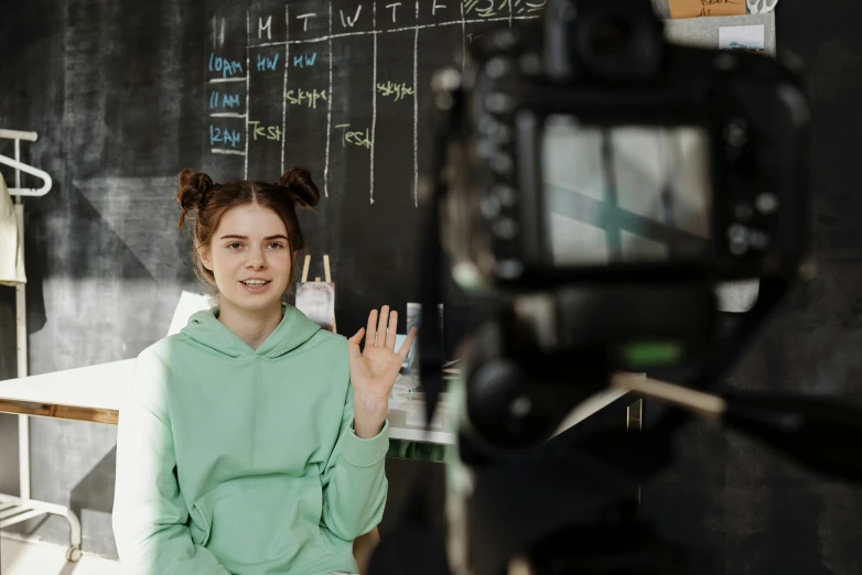 a woman standing in front of a camera, chalkboard, gen z, sitting in the classroom, promo image