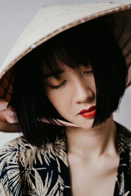 a close up of a person wearing a hat, an album cover, inspired by Itō Shinsui, trending on pexels, vietnamese woman, with a bob cut, faint red lips, casual photography