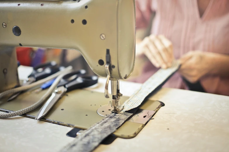 a woman is working on a sewing machine, unsplash, private press, straps, metal garments, thumbnail, digital image