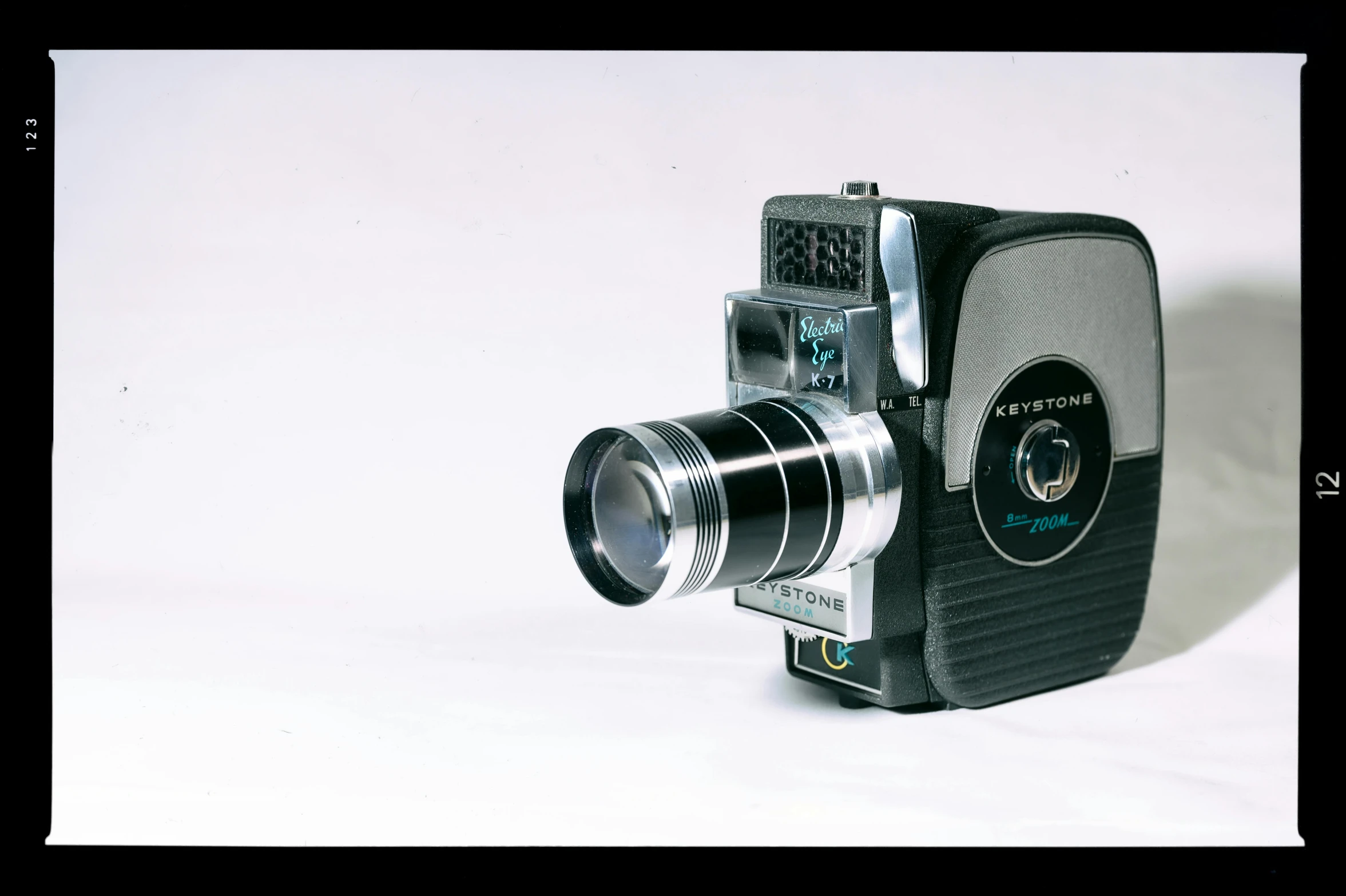 a black and silver camera on a white surface, by Sven Erixson, unsplash, photorealism, super 8 mm, 1960s technicolor, medium format, 5 0 mm 1 9 4 6 historical photo