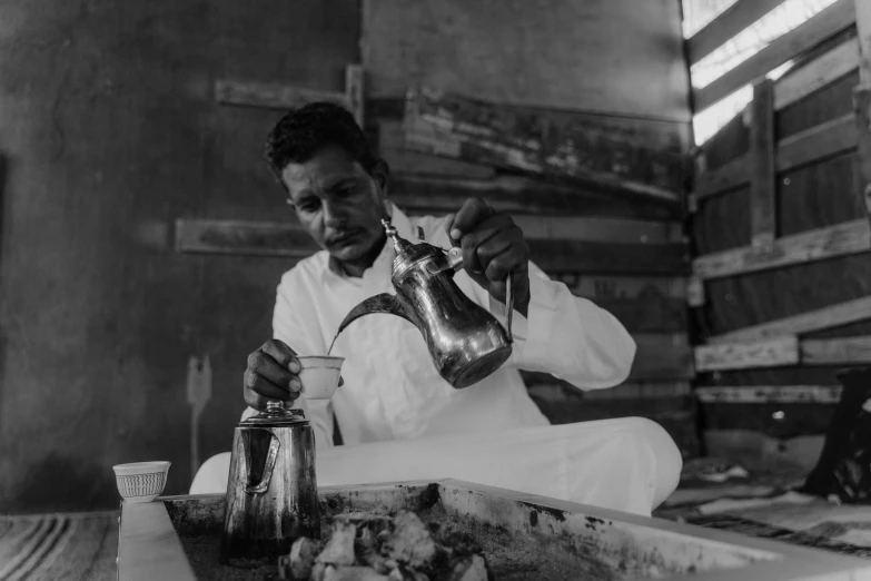 a black and white photo of a man pouring tea, a black and white photo, nubian, making of, lowres, gif