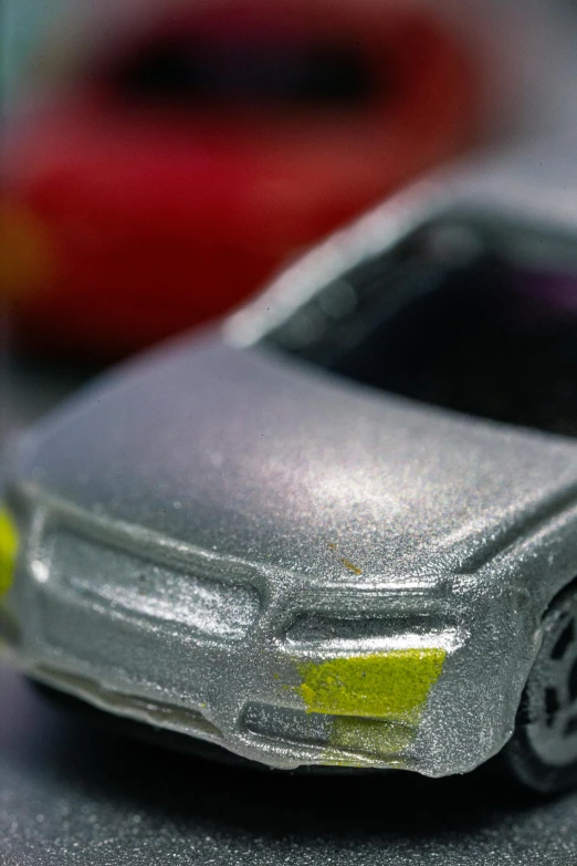 a close up of a toy car on a table, by Tom Bonson, pearlescent, made of nanomaterials, zoomed in, plastic sheen