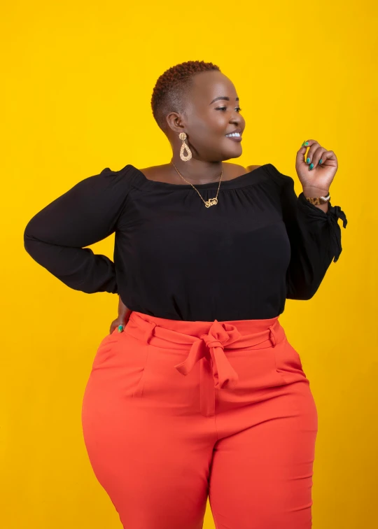 a woman in a black top and orange pants, by Ingrida Kadaka, trending on pexels, full figured, solid background, unmistakably kenyan, red yellow black