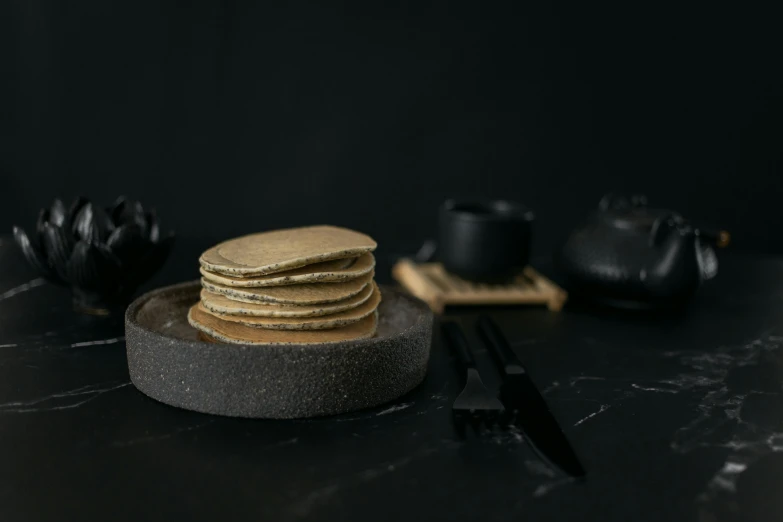 a stack of pancakes sitting on top of a plate, a still life, unsplash, mingei, background image, dark grey, miniature product photo