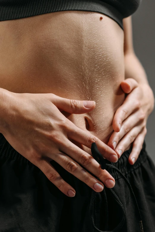 a woman with her hands on her stomach, zoomed in, folds, promo image, photo of a man