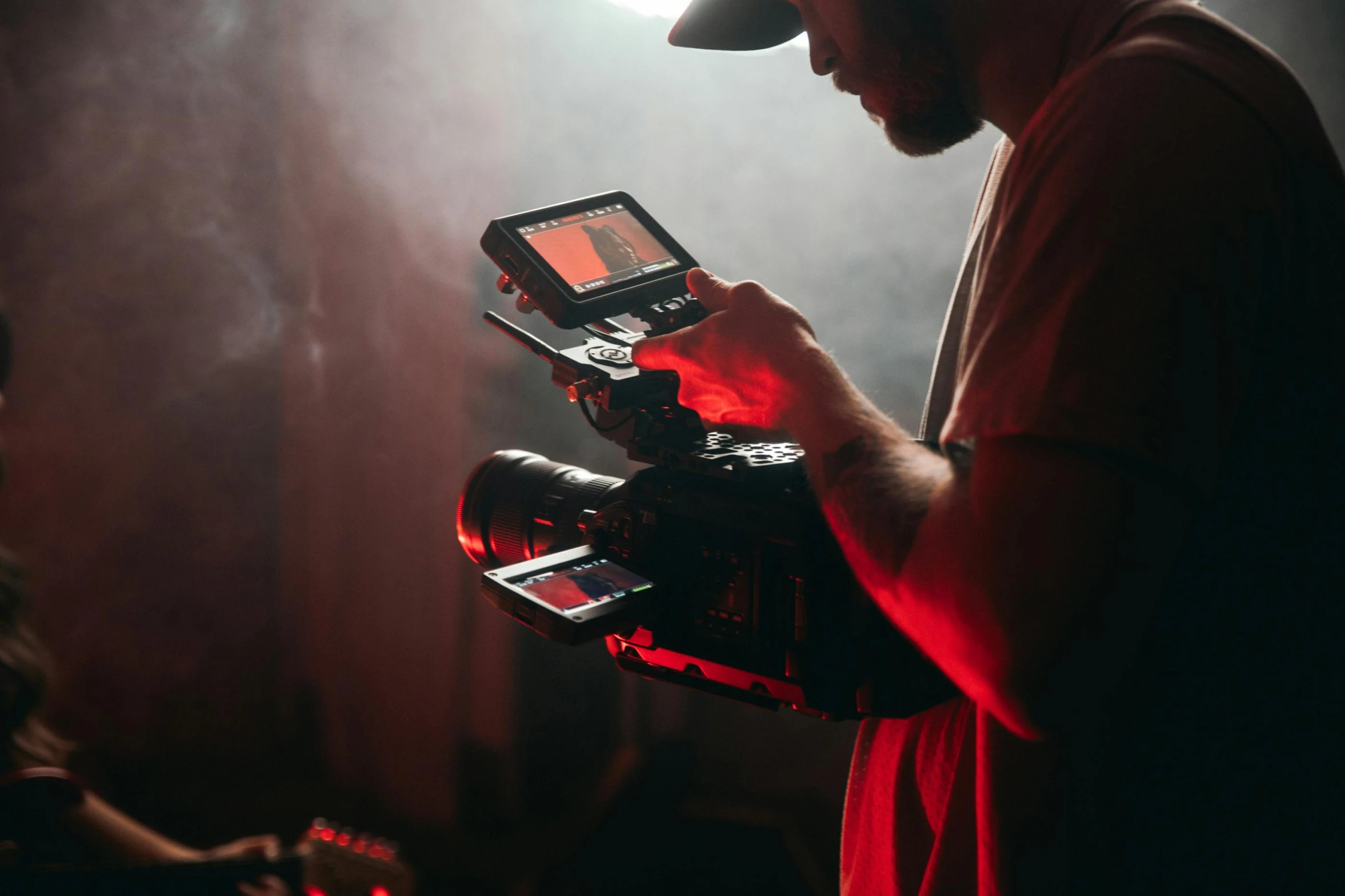 a man holding a camera in front of a red light, production ig, music being played, with dramatic lighting, worksafe. cinematic