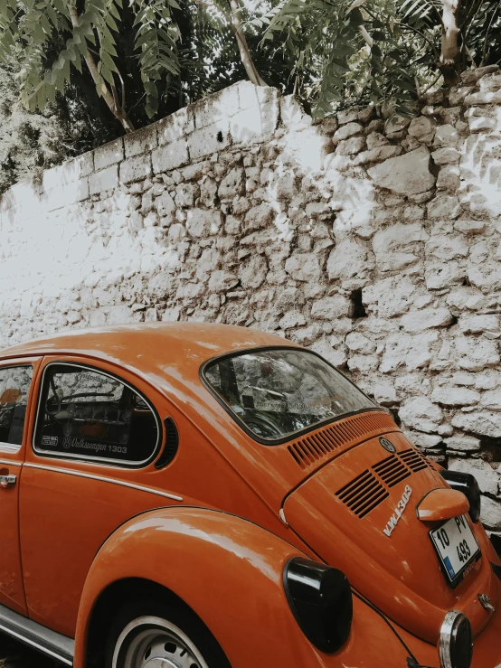 an orange car parked next to a stone wall, a photo, pexels contest winner, hyperrealism, beetle, trending on vsco, 🚿🗝📝, profile image