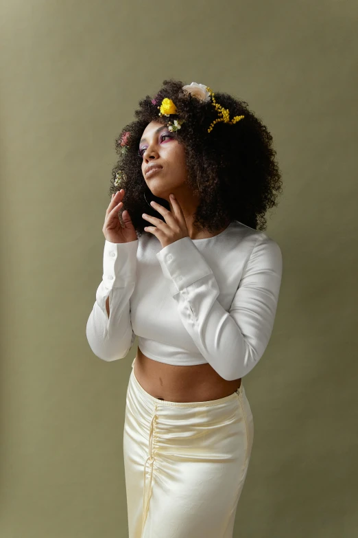 a woman in a white top and skirt talking on a cell phone, an album cover, trending on pexels, renaissance, afro made of flowers, hands in her hair. side-view, neutral pose, 2 4 year old female model