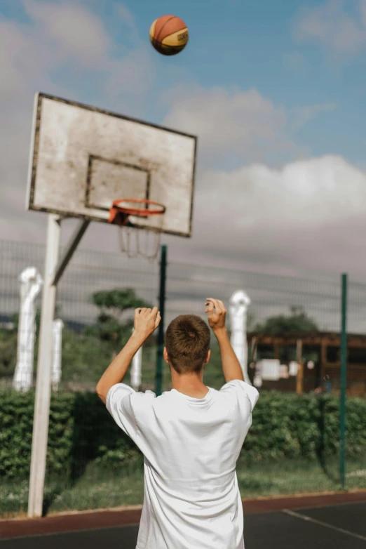 a young man throwing a basketball into the air, pexels contest winner, happening, view from the back, aged 13, proud looking, holding court