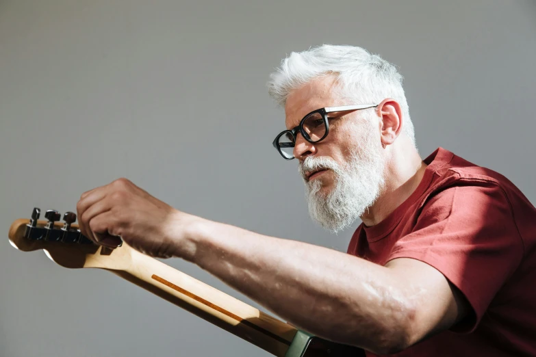 a man with a beard playing a guitar, pexels contest winner, hyperrealism, white reading glasses, easel, gray haired, holding wood saw