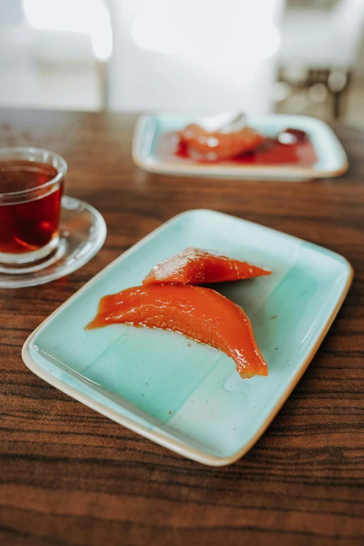 two pieces of salmon on a plate next to a cup of tea, inspired by Modest Urgell, hurufiyya, gummy candies, curated collection, turkey, turquoise and venetian red