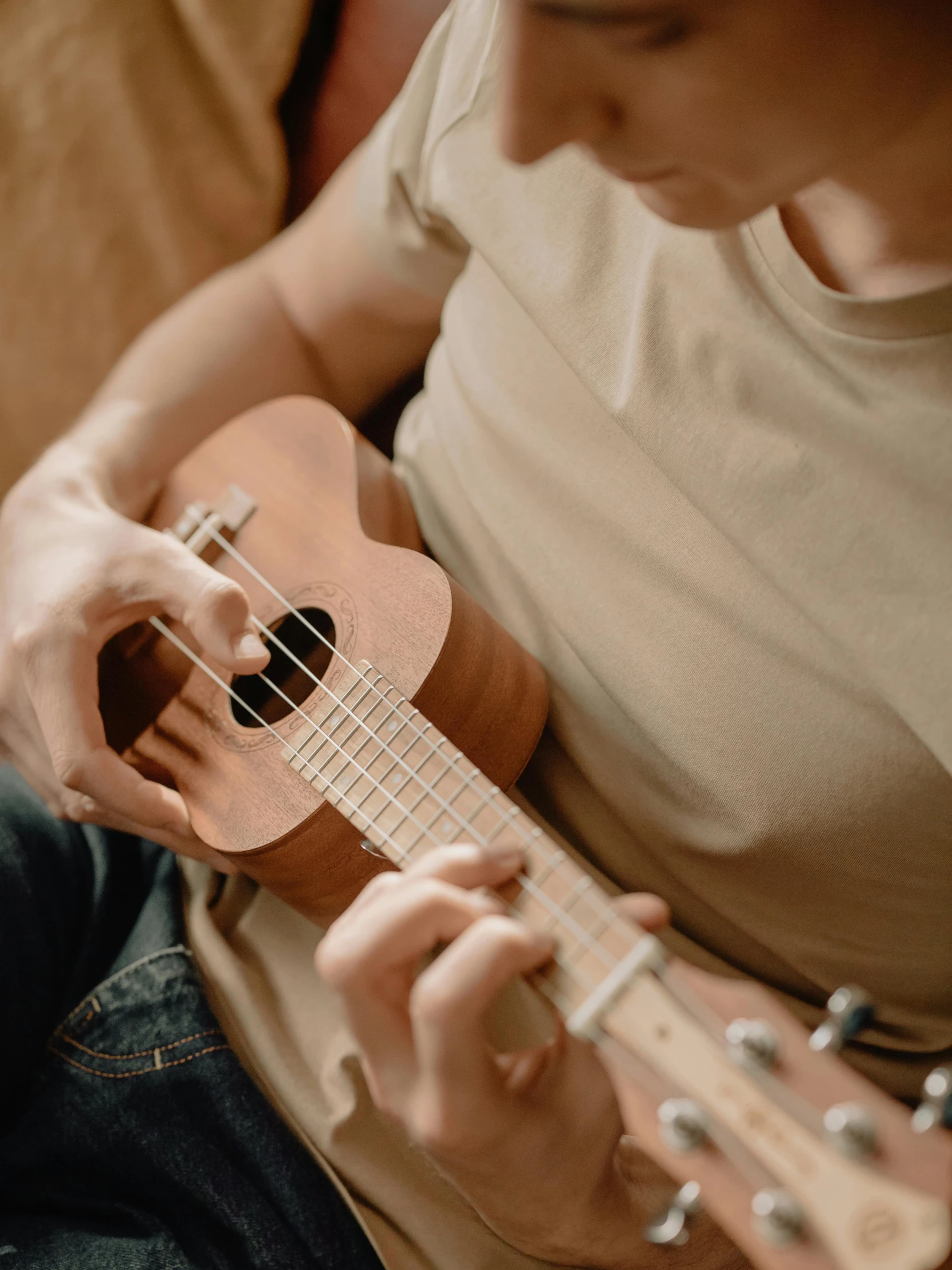 a person sitting on a couch playing a guitar, trending on pexels, ukulele, avatar image, profile image, slightly tanned