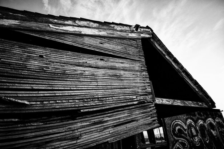 a black and white photo of an old building, unsplash, reclaimed lumber, angled shot, taken at golden hour, covered with tar