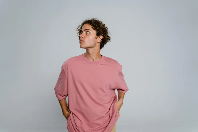 a man standing with his hands in his pockets, trending on pexels, pink, he has short curly brown hair, 18 years old, solid colours