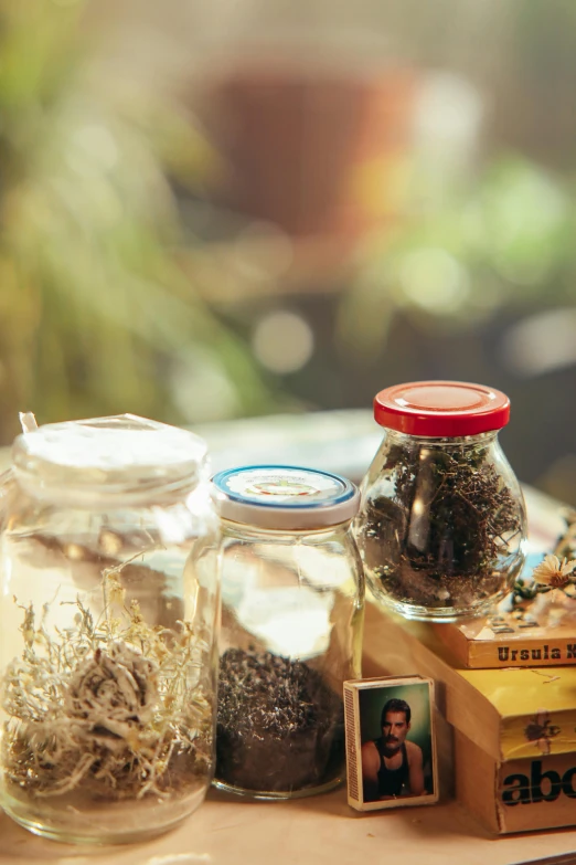 a couple of jars sitting on top of a table, a picture, by Julia Pishtar, unsplash, dried herbs, 15081959 21121991 01012000 4k, sparkling in the sunlight, cigarrette boxes at the table