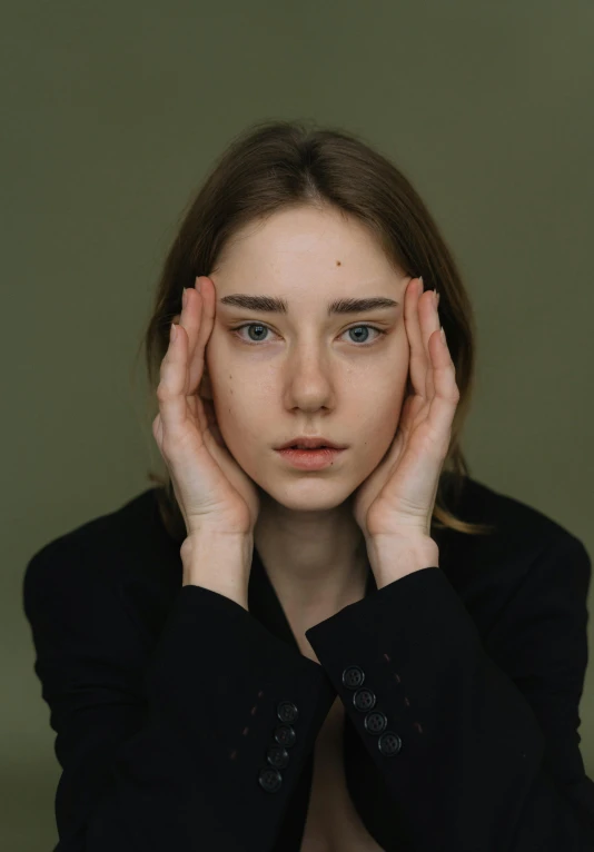 a woman holding her hands to her face, a picture, trending on pexels, hyperrealism, square face, portrait androgynous girl, professional photo, sad green eyes