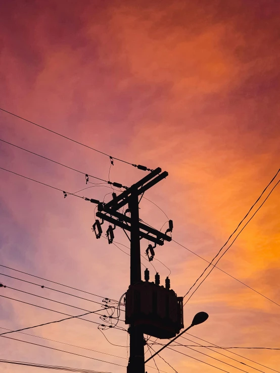 a telephone pole is silhouetted against a colorful sky, inspired by George Pirie, pexels contest winner, electricity archs, overlooking, low quality photo, a wooden