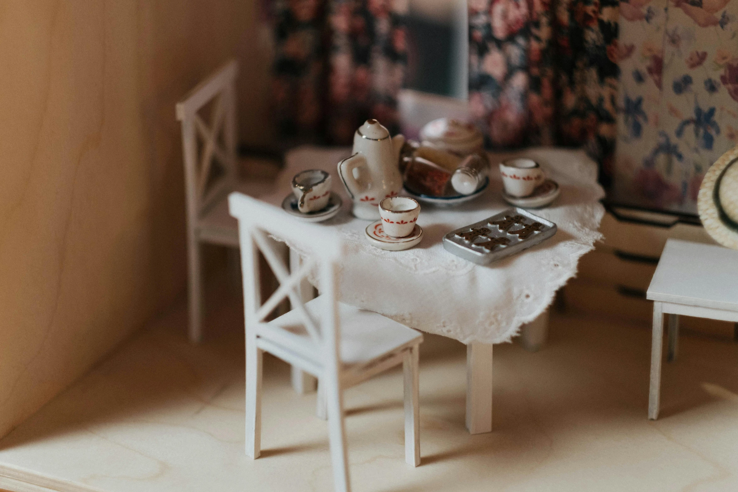 a miniature table and chairs in a doll house, by Sylvia Wishart, unsplash, tea party, white tablecloth, detailed clay model, interior of a small room