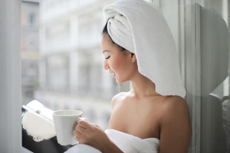 a woman with a towel wrapped around her head holding a cup, pexels contest winner, renaissance, reading the book about love, balcony, clean face and body skin, celebration of coffee products