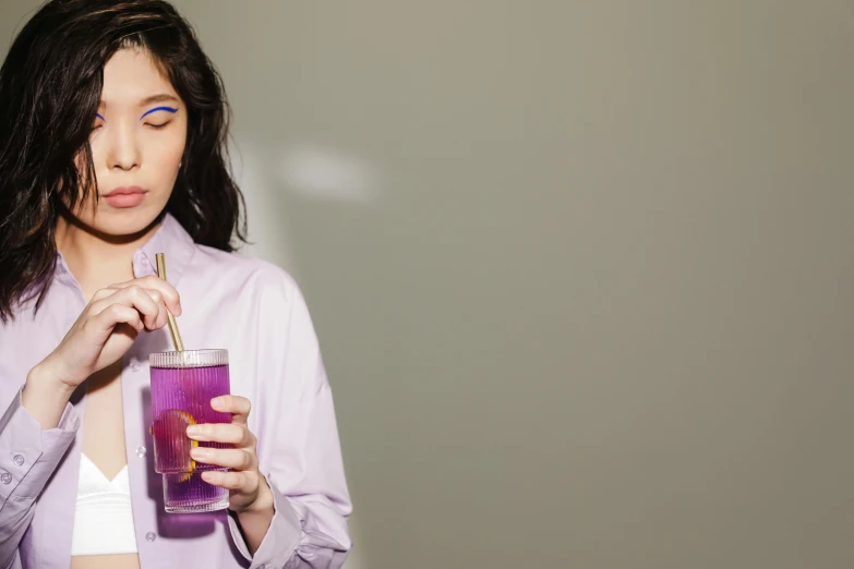 a woman holding a glass of purple liquid, an album cover, trending on pexels, gemma chan girl portrait, juice, lilly collins, cynthwave