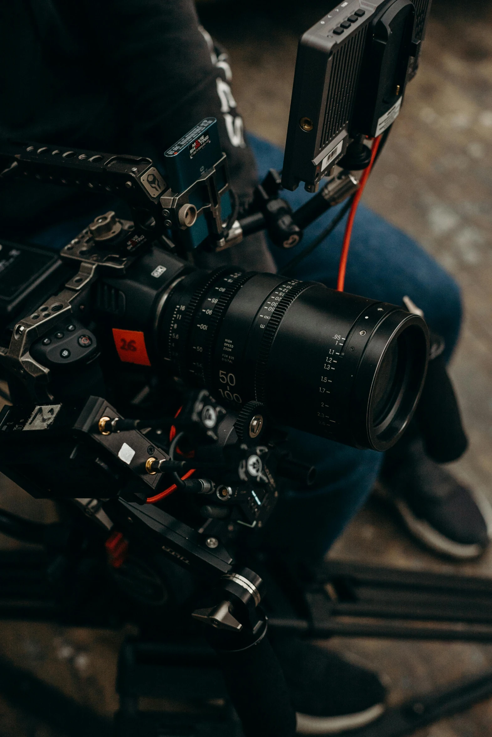 a person holding a camera on a tripod, shot on anamorphic lenses, looking down on the camera, production ready, red camera