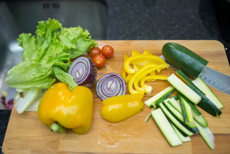 a wooden cutting board topped with vegetables and a knife, a picture, by Dan Content, multicoloured, lettuce, medium close shot, uncrop