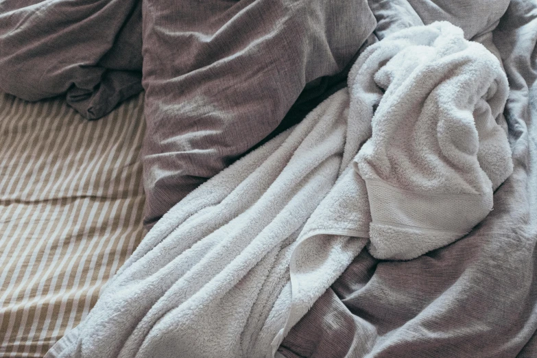 a pile of blankets sitting on top of a bed, trending on pexels, curled up under the covers, very grainy image, wearing a towel, two exhausted