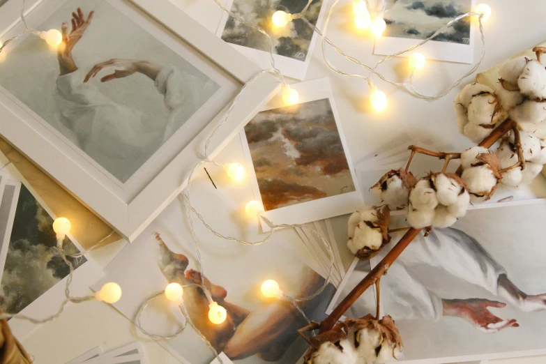 a bunch of pictures sitting on top of a table, inspired by Elsa Bleda, pexels contest winner, string lights, cream and white color scheme, light watercolour, photorealistic image