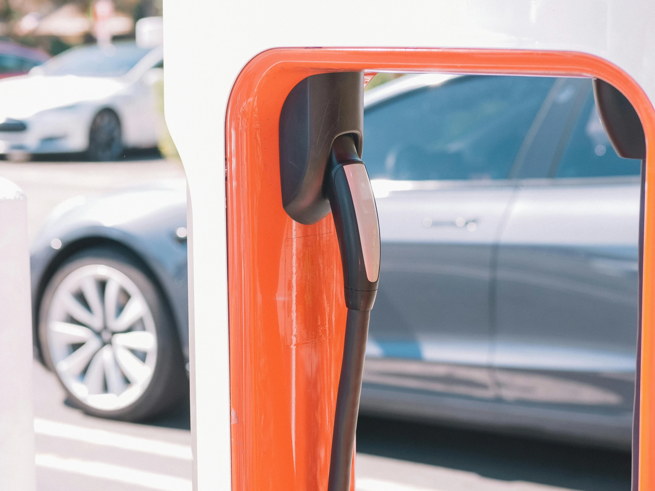 an electric vehicle charging station with a car in the background, unsplash, photorealism, orange and white color scheme, square, viewed through the cars window, closeup - view