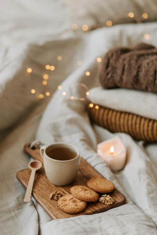 a tray of cookies and a cup of coffee on a bed, trending on pexels, romanticism, floating lights, linen, winter setting, gif